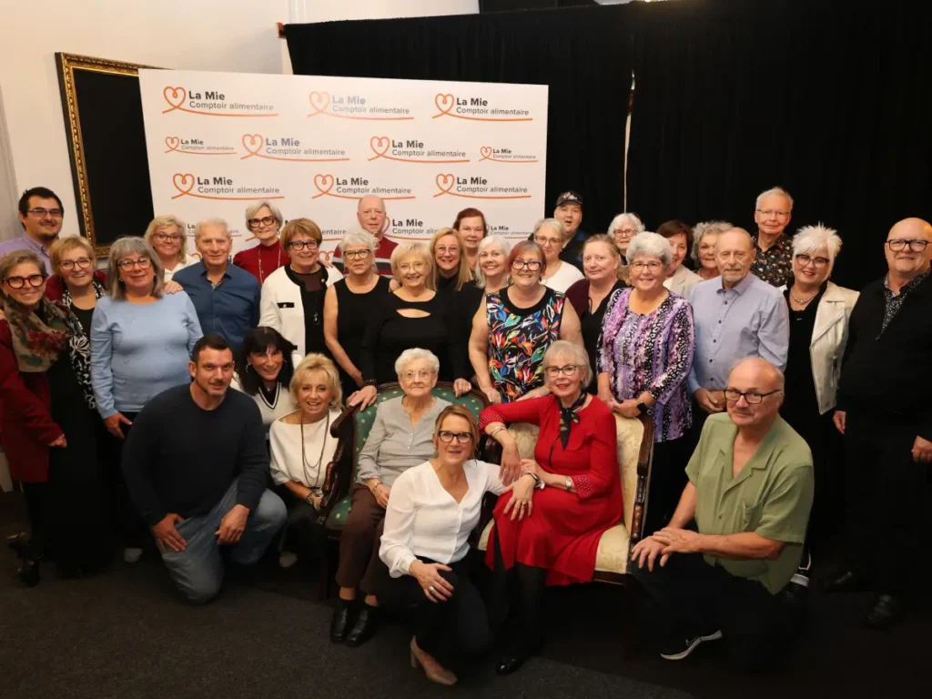 Bénévoles de La Mie réunis devant le panneau du comptoir alimentaire lors du souper-bénéfice 2026, à Saint-Hyacinthe